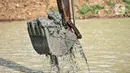 Petugas Sudin SDA Jakarta Timur menggunakan alat berat untuk mengeruk lumpur di Waduk Setu, Cipayung, Jakarta, Rabu (28/7/2021). Pengerukan lumpur ini dilakukan untuk mencegah terjadinya banjir saat musim hujan. (merdeka.com/Iqbal S. Nugroho)