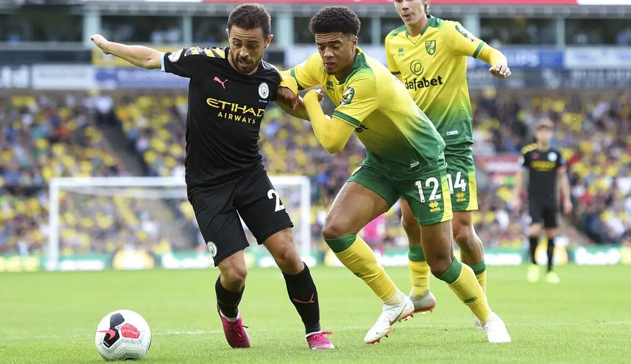 Pemain Norwich City, Jamal Lewis, berebut bola dengan gelandang Manchester City, Bernardo Silva, pada laga Premier League di Stadion Carrow Road, Sabtu (14/9). Norwich City menang 3-2 atas Manchester City. (AP/Joe Giddens)