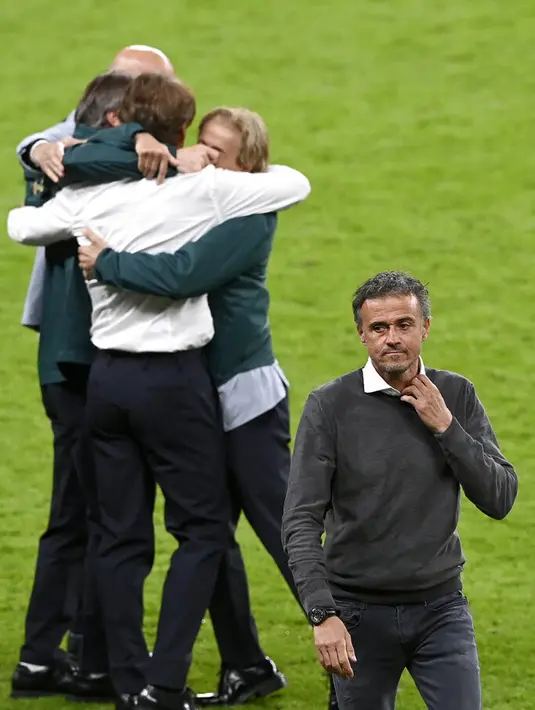 Pelatih Spanyol Luis Enrique berjalan pergi ketika pelatih Italia Roberto Mancini merayakan di latar belakang pada akhir pertandingan semifinal Euro 2020 di Stadion Wembley di London, Inggris, Rabu (7/7/2021). (Facundo Arrizabalaga/Pool Photo via AP)