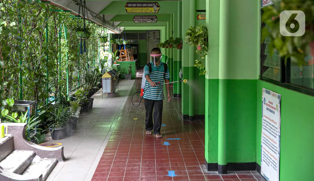 Seorang guru mendisinfeksi SDN Kenari 08, Jakarta, Selasa (6/4/2021). Uji coba pembelajaran tatap muka terbatas di DKI Jakarta akan dilakukan dengan menerapkan protokol kesehatan COVID-19 yang ketat. (Liputan6.com/Faizal Fanani)