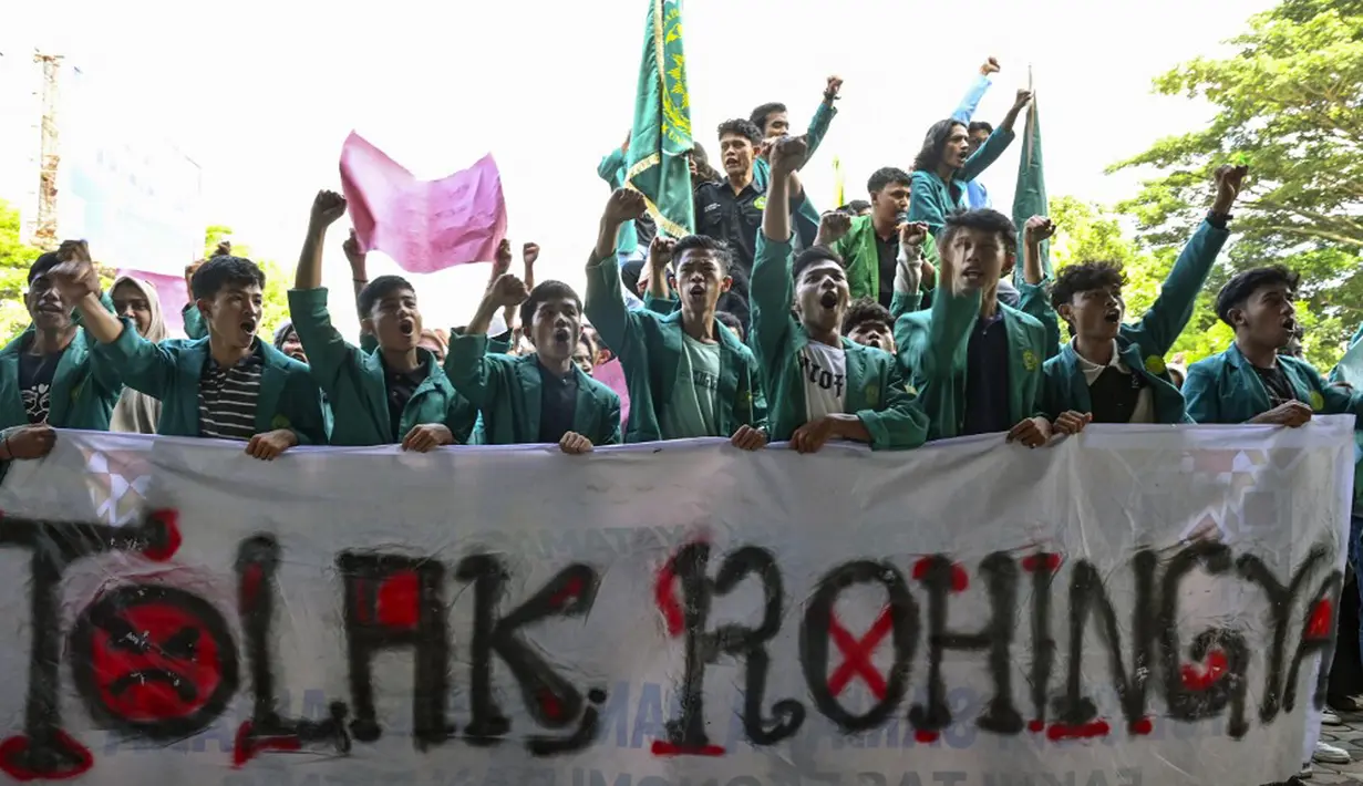 Mahasiswa memegang spanduk bertuliskan “Tolak Rohingya” saat berdemonstrasi menentang kedatangan pengungsi Rohingya di depan Dewan Perwakilan Rakyat (DPR) di Banda Aceh, Rabu (27/12/2023). Aksi diikuti oleh ratusan mahasiswa dari berbagai universitas. (CHAIDEER MAHYUDDIN/AFP)