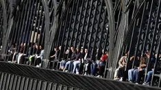 Kaum muda menikmati matahari terbenam di jembatan 'Hackerbruecke' di Munich, Jerman, Minggu, (28/3/2021). Hackerbrücke (Hacker Bridge) adalah jembatan jalan raya yang melintasi jalur kereta api utama di Munich tepat di sebelah barat stasiun pusat kota. (AP Photo/Matthias Schrader)