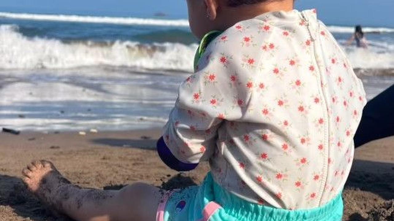 Potret Baby Djiwa sedang duduk di atas pasir pantai.
