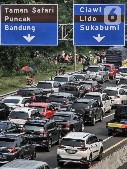 Kendaraan wisatawan terjebak penutupan jalur Puncak akibat sistem satu arah di Tol Jagorawi, Pandansari, Bogor, Jawa Barat, Minggu (19/9/2021). Lamanya penutupan memaksa wisatawan turun dari mobil dan beristirahat di pinggir jalan tol. (merdeka.com/Iqbal S. Nugroho)