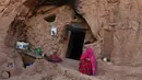 Seorang wanita duduk di pintu masuk gua di kota Bamiyan, Kabul. Foto diambil pada 19 Juni 2015. Ratusan warga miskin Afghanistan terpaksa menghuni gua-gua tersebut untuk dijadikan rumah karena tak memiliki tempat tinggal. (AFP PHOTO / SHAH Marai)