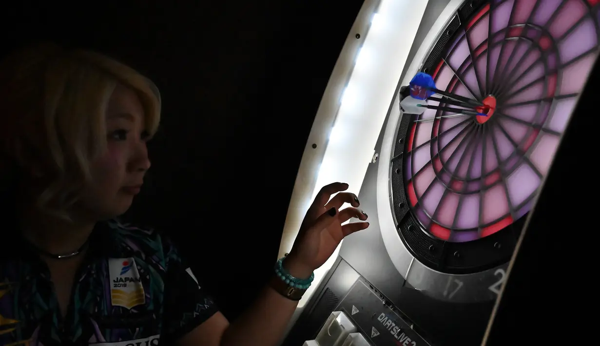 Mikuru Suzuki memeriksa hasil lemparan anak panahnya saat bermain darts di Tokyo, Jepang, 8 April 2019. Suzuki disebut-sebut sebagai Phil Taylor wanita, pemain darts profesional asal Inggris. (CHARLY TRIBALLEAU/AFP)
