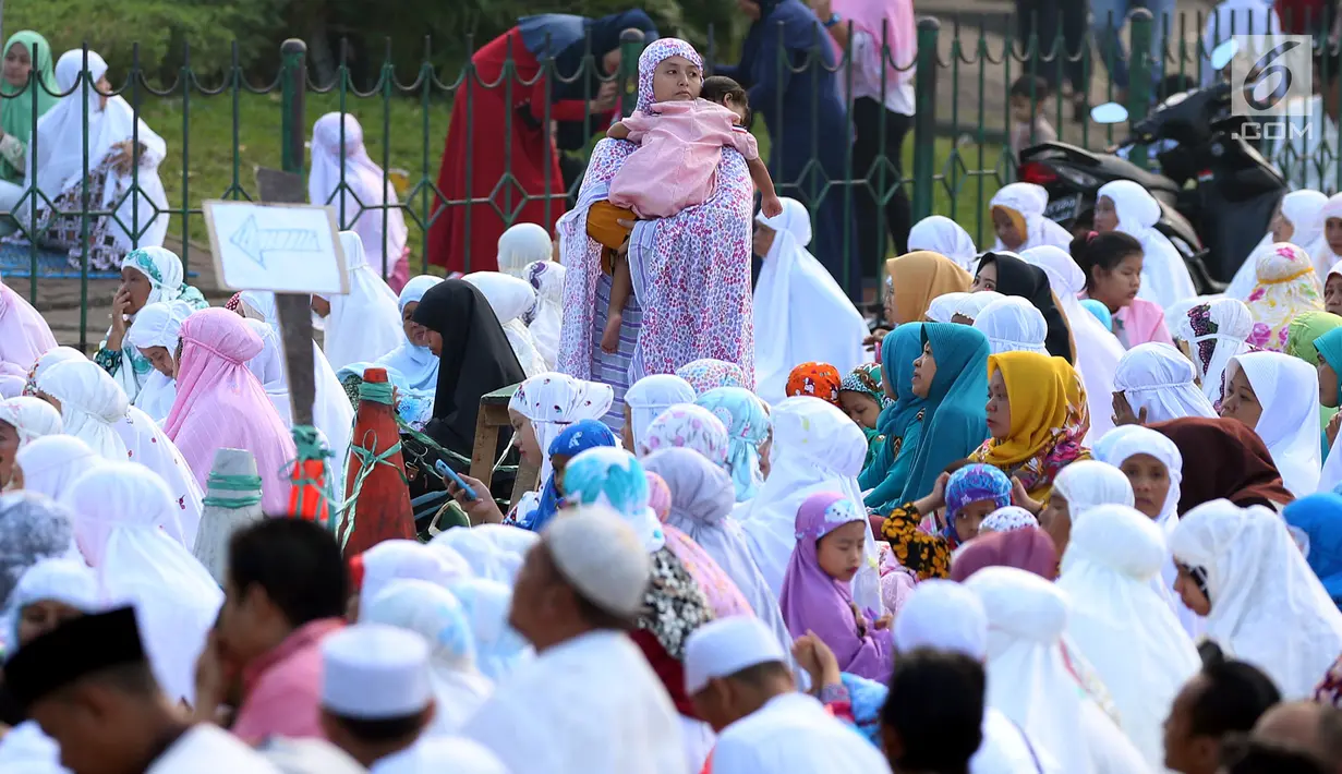 Seorang ibu menggendong anaknya sambil mendengarkan khotbah usai Salat Idul Fitri di kawasan Senen, Minggu (25/6). Hari Raya Idul Fitri 1438 H disambut umat muslim dengan melaksanakan salat Ied di masjid dan tempat terbuka. (Liputan6.com/Johan Tallo)