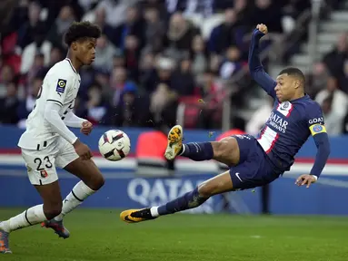 Penyerang Paris Saint-Germain (PSG) Kylian Mbappe menendang bola di sebelah bek Rennes, Warmed Omari pada  Ligue 1 2022/2023 pekan ke-28 di Parc des Princess, Senin (20/3/2023). (AP Photo/Christophe Ena)
