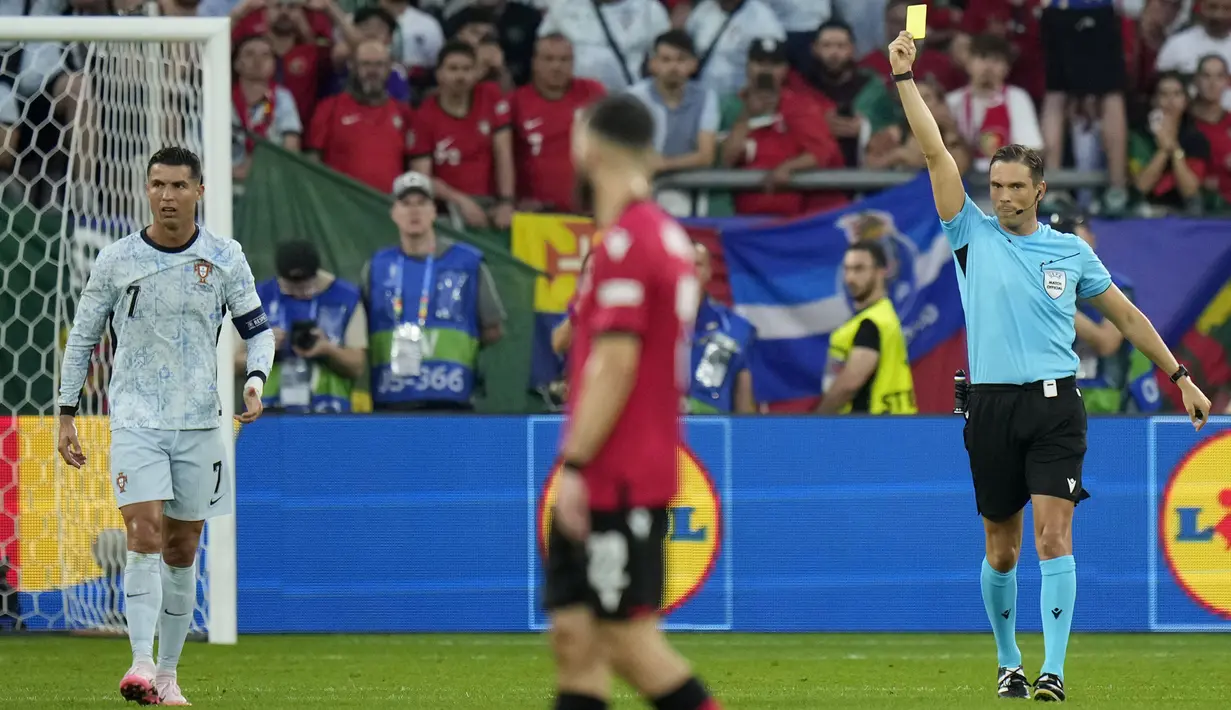 Pemain Portugal, Cristiano Ronaldo (kiri) mendapatkan kartu kuning dari wasit saat laga Grup F Euro 2024 melawan Georgia di Arena AufSchalke, Gelsenkirchen, Jerman, Kamis (27/06/2024) dini hari WIB. (AP Photo/Alessandra Tarantino)