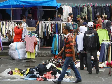 Pedagang menjajakan pakaian bekas di kawasan Pasar Senen, Jakarta, Senin (23/1). Pascakebakaran beberapa hari lalu, para pedagang terpaksa berjualan di luar gedung, meskipun menutup jalan dan mengganggu arus lalu lintas. (Liputan6.com/Immanuel Antonius)