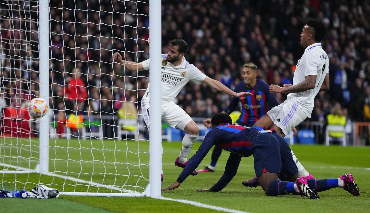 Pemain Real Madrid, Eder Militao (kanan) mencetak gol bunuh diri pada laga leg pertama semifinal Copa Del Rey 2022/2023 melawan Barcelona di Santiago Bernabeu, Madrid, Jumat (03/03/2023) WIB. Gol ini menjadi satu-satunya gol yang berhasil memenangkan Barcelona dengan skor 1-0. (AP Photo/Manu Fernandez)