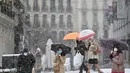 Orang-orang berjalan saat salju turun di Madrid, Spanyol, Jumat (8/1/2021). Salju tebal menutupi hingga setengah dari Spanyol dan menyebabkan penurunan suhu yang besar. (GABRIEL BOUYS/AFP)