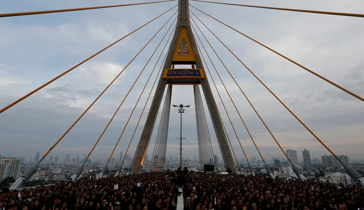 Ribuan warga hadir mengenakan baju hitam-hitam saat acara HUT terakhir almarhum Raja Thailand, Bhumibol Adulyadej di atas Jembatan Bhumibol, Bangkok, Thailand, Senin (5/12). Raja Bhumibol meninggal di usia 88 tahun. (REUTERS/Jorge Silva)