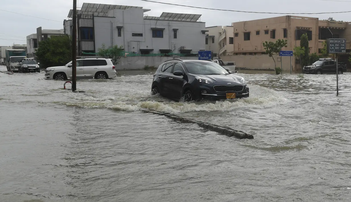 Mobil melewati jalan yang banjir setelah hujan muson yang lebat di Karachi (26/7/2022). Keadaan darurat cuaca diumumkan di Karachi karena hujan muson yang lebih deras dari biasanya terus melanda kota terbesar di Pakistan, membanjiri rumah-rumah dan membuat jalan-jalan tidak dapat dilalui. (AFP/Asif Hassan)