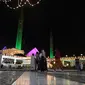 Orang-orang melewati bangunan masjid Faisal yang diterangi selama perayaan hari kelahiran Nabi Muhammad SAW atau Maulid Nabi di Islamabad, Pakistan, Senin (18/10/2021). Peringatan Maulid Muhammad tak hanya diperingati umat Islam di Indonesia, tapi juga di berbagai negara. (Farooq NAEEM/AFP)