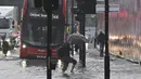 Seorang pejalan kaki melintasi perairan dalam di jalan yang banjir di distrik The Nine Elms London(25/7/2021). Bus dan mobil terjebak banjir ketika jalan-jalan di London banjir pada hari Minggu, ketika badai petir berulang kali melanda ibu kota Inggris. (AFP/Justin Tallis)