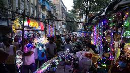 Pelanggan berjalan melewati deretan kios yang menjual lampu hias menjelang Diwali, festival lampu Hindu, di Kolkata, India, Rabu (27/10/2021). Diwali adalah salah satu festival paling penting dalam agama Hindu, yang didedikasikan untuk ibadah Dewi Laksmi. (AP Photo/Bikas Das)