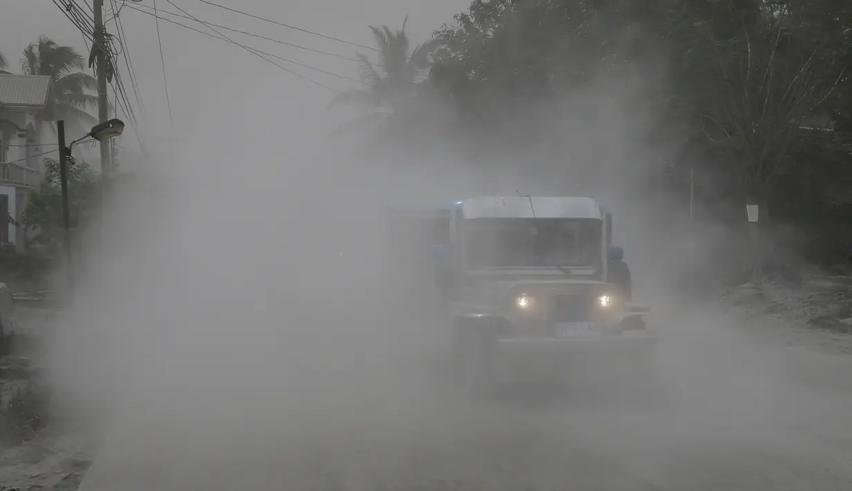 Sebuah jip melewati jalan yang tertutup abu vulkanik selama evakuasi saat gunung berapi Taal meletus di Lemery, provinsi Batangas, Filipina, Senin (13/11/2020). Erupsi gunung Taal memaksa puluhan ribu orang mengungsi serta membuat sekolah-sekolah dan toko di Manila tutup. (AP/Aaron Favila)