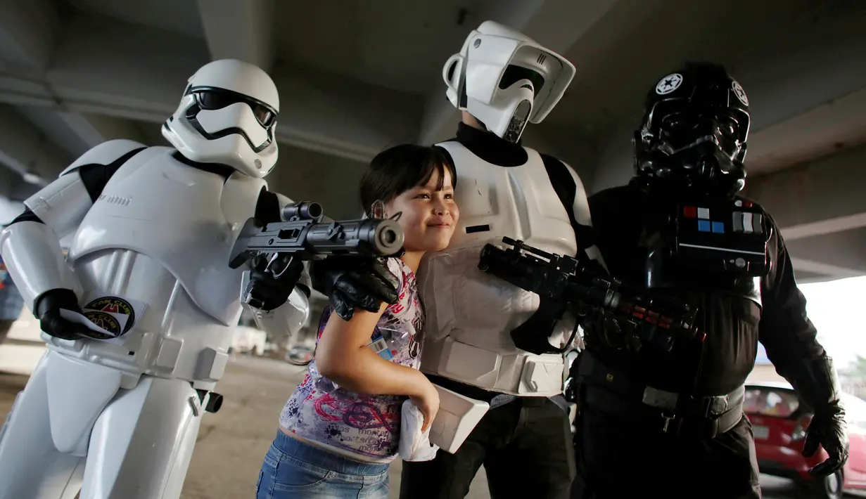 Anggota klub penggemar Star Wars berkostum Stormtrooper (kiri), Scout Trooper (tengah) dan Imperial Tie Percontohan berfoto bersama gadis cilik selama perayaan Star Wars Day di sebuah rumah sakit di Monterrey, Meksiko, Rabu (4/5).(REUTERS/Daniel Becerril)
