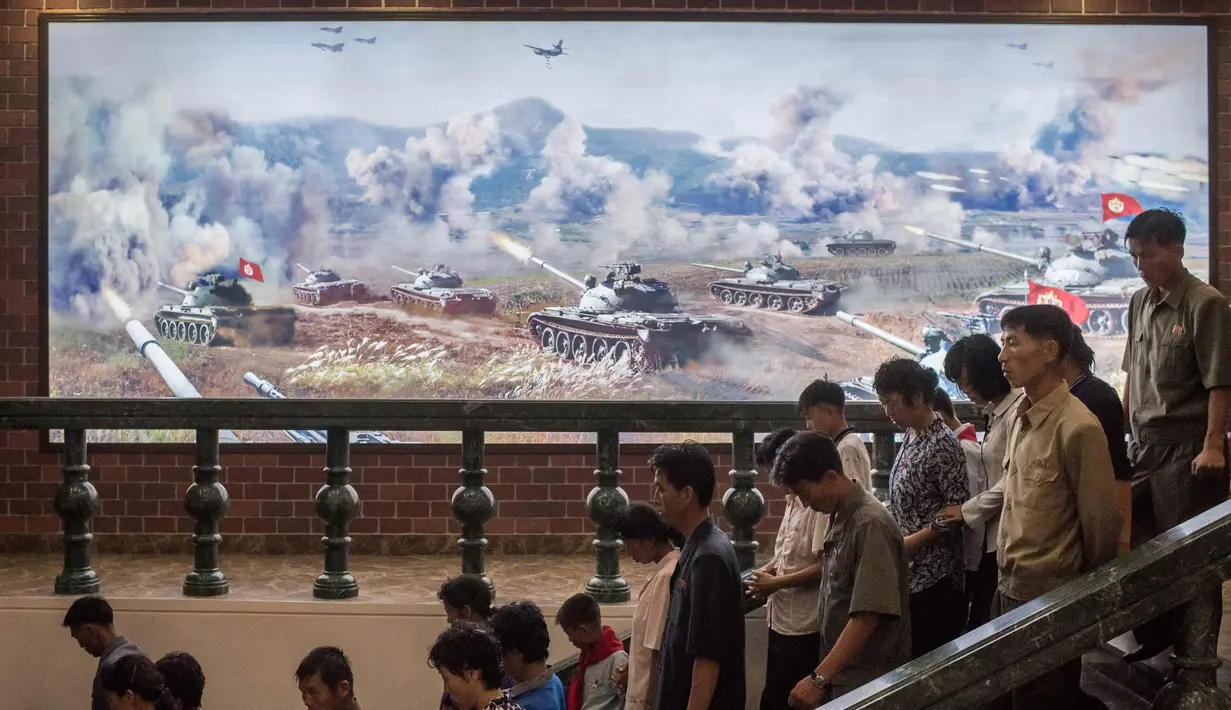Foto yang diambil 24 Juli 2017. Pengunjung melintas di depan lukisan yang menunjukkan sejumlah tank saat berperang di Sinchon Museum of American War Atrocities, Sinchon, Pyongyang. Museum ini didedikasikan kepada Pembantaian Sinchon. (AFP Photo/Ed Jones)