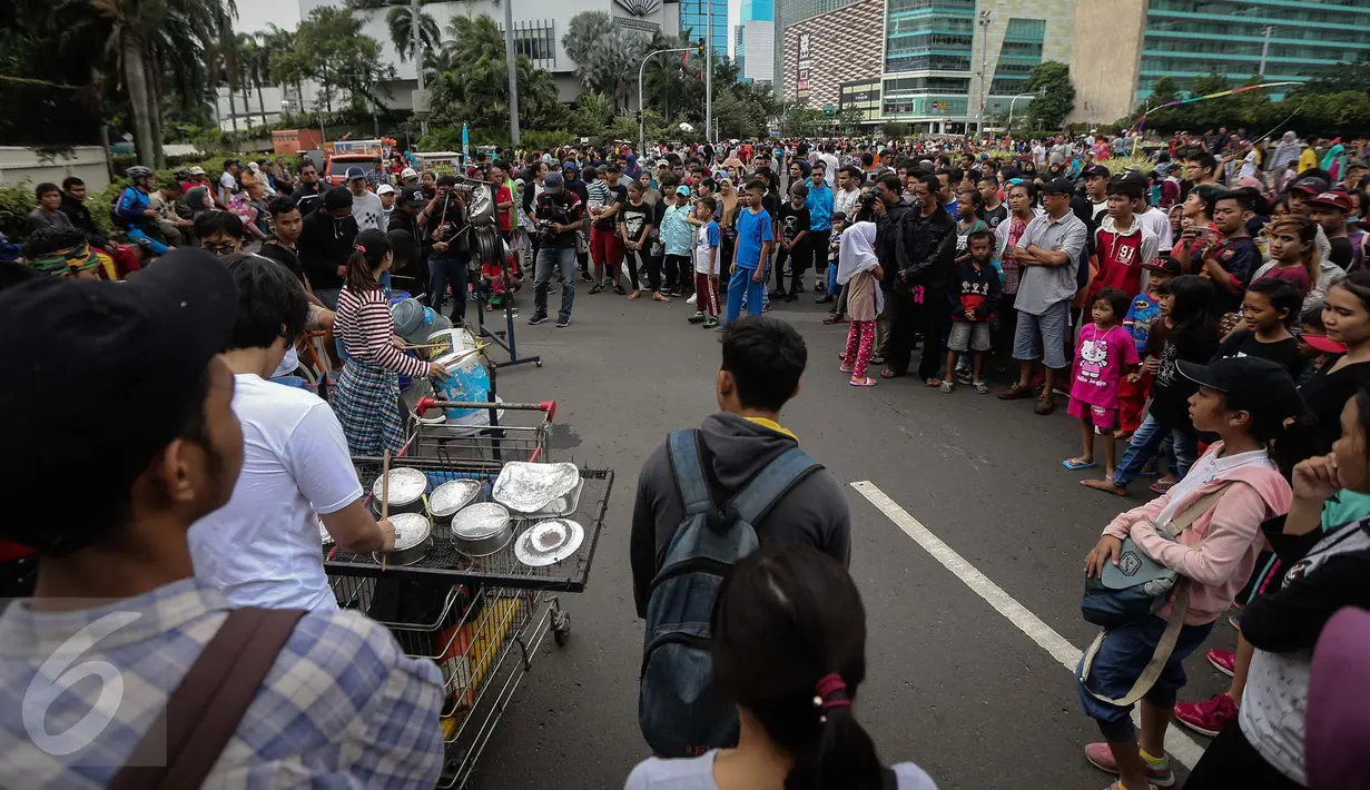 Warga melihat atraksi musik menggunakan barang-barang bekas di Car Free Day kawasan Bundaran HI, Jakarta, Minggu (15/1). (Liputan6.com/Faizal Fanani)