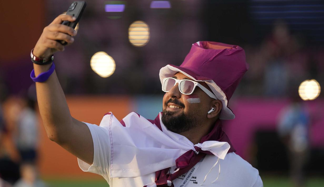 Pendukung Timnas Qatar melakukan swafoto saat menunggu pembukaan Piala Dunia 2022 di Hayya Fan Zone, Lusail pada Minggu (20/11/2022). (AP/Lee Jin-man)