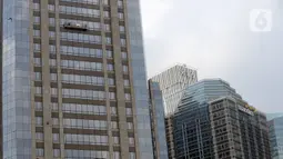 Pekerja membersihkan kaca gedung bertingkat di kawasan Sudirman Central Business District (SCBD), Jakarta, Senin (8/6/2020). Hampir tiga bulan kebijakan work from home (WFH) akibat pandemi COVID-19, banyak gedung bertingkat tidak terawat hari ini mulai dibersihkan. (merdeka.com/Dwi Narwoko)