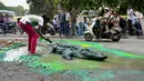 Seniman Baadal Nanjundaswamy saat menyelesaikan boneka buaya di atas jalan berlubang di Sultanpalya, Bangalore, India, Kamis (18/6/2015). Aksi protes tersebut untuk mendesak pemerintah agar segera memperbaiki jalan yang rusak. (AFP PHOTO/ Manjunath KIRAN)