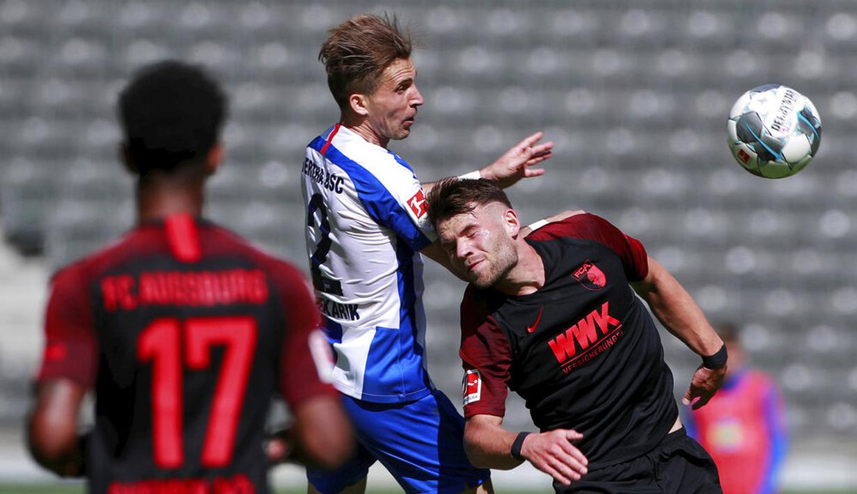 Pemain Hertha Berlin, Peter Pekarik, berebut bola dengan pemain Augsburg, Eduard Lowen, pada laga Bundesliga di Olympiastadion, Sabtu (30/5/2020). Hertha Berlin menang 2-0 atas Augsburg. (AP/Hannibal Hanschke)