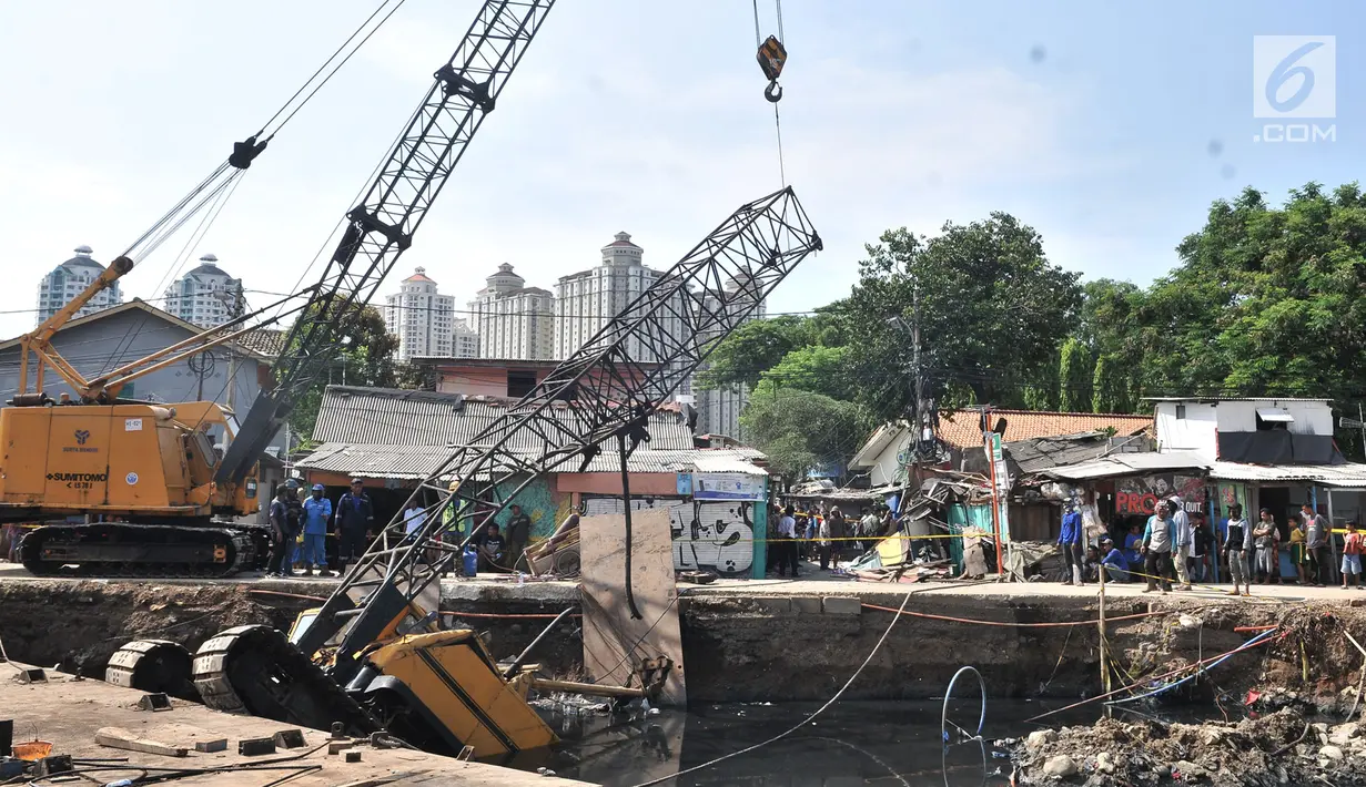 Petugas melakukan evakuasi crane jatuh di kawasan Kemayoran, Jakarta, Kamis (6/12). Crane yang digunakan untuk pembangunan turap Kali Sentiong tersebut jatuh hingga menimpa rumah warga dan menyebabkan tiga orang luka-luka. (Merdeka.com/Iqbal S. Nugroho)