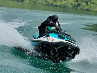 Mengenakan gamis syar'i lengkap dengan jilbab panjang, Umi Pipik tetap terlihat santai saat mengendalikan jet ski. Ia menyusuri perairan Danau Toba selama 45 menit dengan rute dari Samosir hingga Toba. Meskipun menggunakan pakaian tertutup, ia tetap lincah dan fokus menjaga keseimbangan selama perjalanan. (Liputan6.com/IG/@_ummi_pipik_)