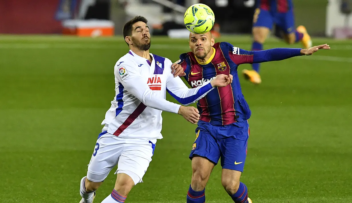 Striker Barcelona, Martin Braithwaite (kanan) berebut bola dengan bek Eibar, Pedro Bigas dalam laga lanjutan Liga Spanyol 2020/21 pekan ke-16 di Camp Nou, Selasa (29/12/2020). Barcelona bermain imbang 1-1 dengan Eibar. (AFP/Pau Barrena)