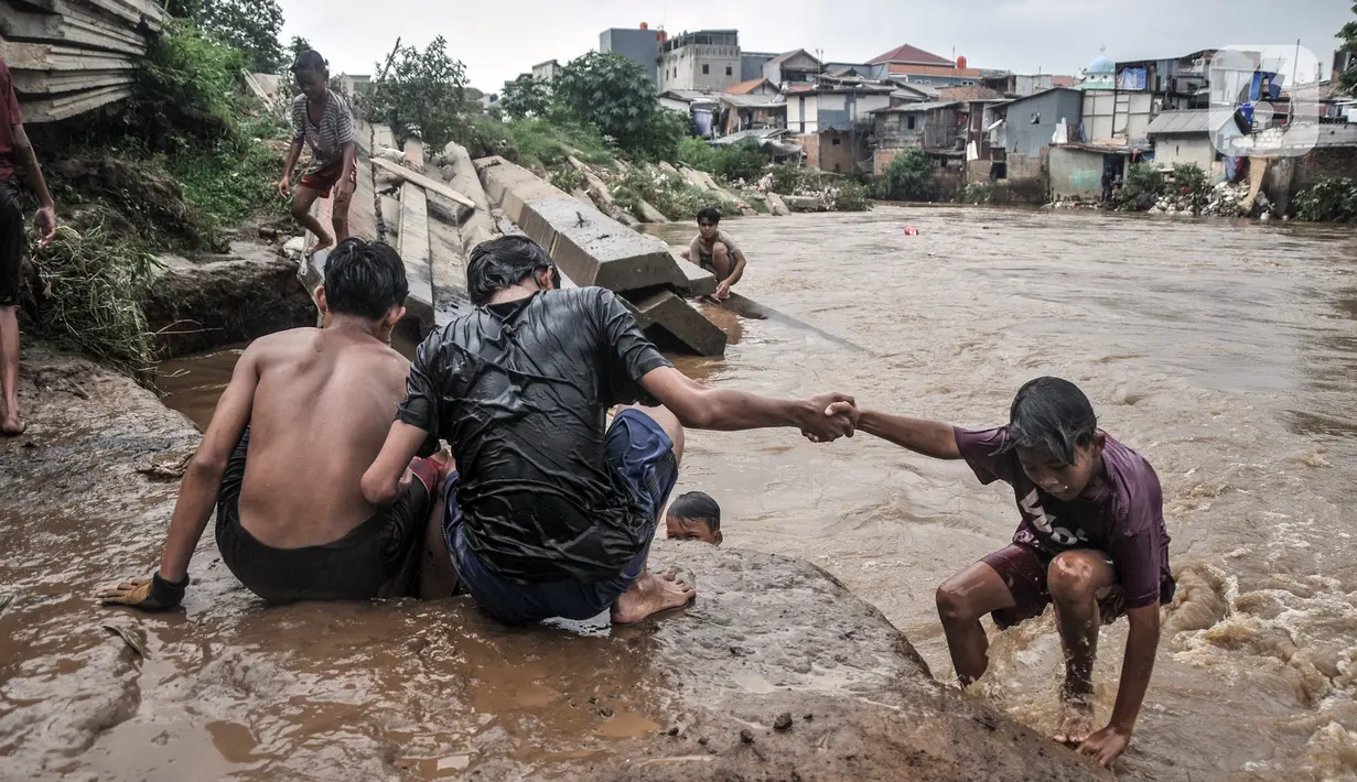 Anak-anak bermain di Kali Ciliwung yang meluap, Kebon Pala, Jatinegara, Jakarta Timur, Minggu (31/10/2021). Aliran Kali Ciliwung yang meluap akibat hujan di kawasan hulu dimanfaatkan anak-anak untuk berenang meski membahayakan keselamatan. (merdeka.com/Iqbal S. Nugroho)