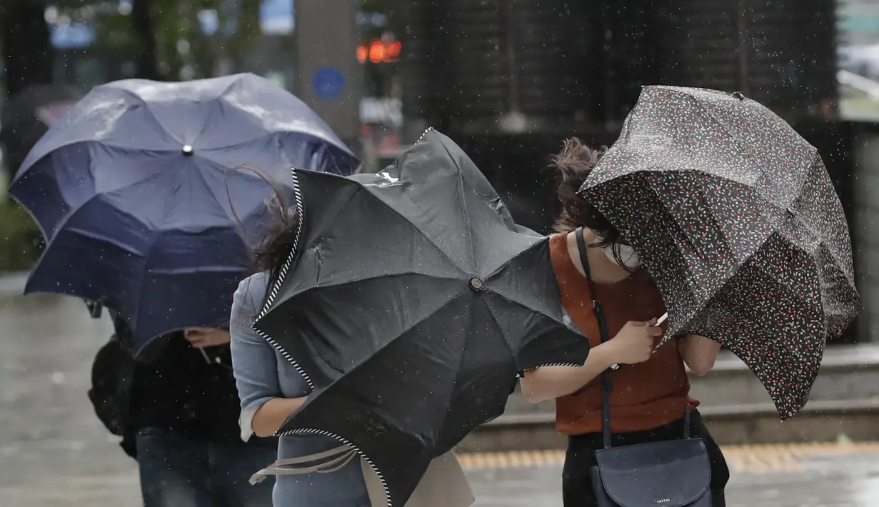 Orang-orang berjuang dengan payung mereka melawan angin kencang dan hujan di pusat kota Seoul, Korea Selatan, Kamisn (3/9/2020). Topan Maysak kuat melanda wilayah semenanjung Korea. (AP Photo/Lee Jin-man)