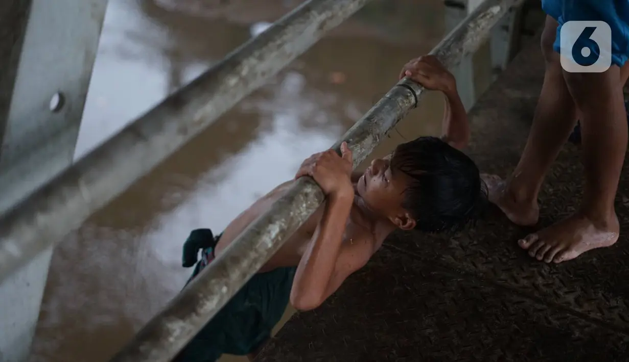 Anak-anak melompat dari jembatan ke Sungai Ciliwung, Rawajati, Jakarta, Selasa (17/12/2019). Meski debit air Sungai Ciliwung naik akibat hujan mengguyur Jakarta sejak siang hingga sore, anak-anak tersebut tetap nekat berenang tanpa memedulikan keselamatan. (Liputan6.com/Immanuel Antonius)