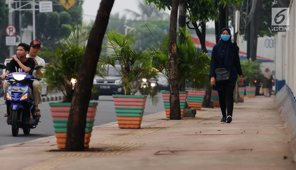 Warga melintasi pedestrian di Jalan TB Simatupang, Jakarta, Jumat (7/7). Pedestrian di Jalan TB Simatupang sekitar perempatan Pasar Rebo menjadi berwarna dengan tampilan pot cat warna warni. (Liputan6.com/Helmi Fithriansyah)