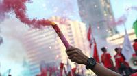 Sejumlah buruh menyalakan bom asap saat menutup aksi Hari Buruh Internasional di Jalan Medan Merdeka Barat, Jakarta, Rabu (5/1/2019). Aksi May Day 2019 di Jakarta ditutup oleh buruh dengan menyalakan kembang api sebagai simbol berjalannya demo dengan damai. (Liputan6.com/Helmi Fithriansyah)