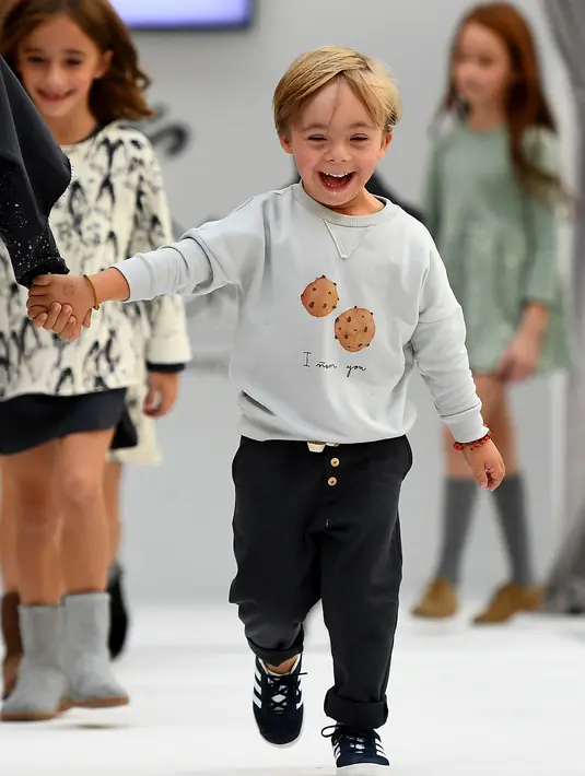 Seorang anak laki-laki dengan down syndrome berjalan di atas catwalk selama pekan mode Petite Fashion Week di Madrid, 6 Oktober 2017. Pendapatan dari acara tersebut disumbangkan untuk Garrigou Foundation dan Prodis Foundation. (GABRIEL BOUYS/AFP)