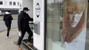 Seorang pria bermasker pergi ke penata rambut yang dibuka kembali setelah pelonggaran lockdown di Wina, Austria, Senin (8/2/2021). Austria mulai melonggarkan lockdown covid-19 ketiga mereka mulai 8 Februari dengan mengizinkan sekolah, museum dan toko dibuka kembali. (AP Photo/Ronald Zak)