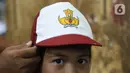 Calon pembeli mencoba topi sekolah kepada anaknya di Pasar Kebayoran Lama, Jakarta, Jumat (8/7/2022). Menjelang dimulainya tahun ajaran baru, para orang tua disibukkan berbelanja baju seragam dan perlengkapan sekolah untuk anak mereka. (Liputan6.com/Angga Yuniar)