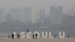 Seorang wanita mengenakan masker berpose saat pemandangan kota ditutupi dengan kabut tebal partikel debu halus di Seoul, Korea Selatan, Selasa (5/3). (AP Photo/Ahn Young-joon)