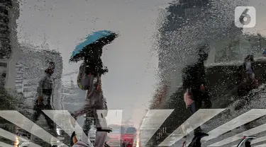 Pekerja melintas di pelican crossing di kawasan Perkantoran Sudirman, Jakarta, Rabu (26/4/2023). (Liputan6.com/Faizal Fanani)