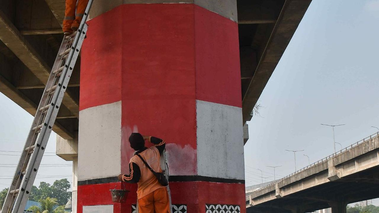 Dua orang petugas Penanganan Prasarana dan Sarana Umum (PPSU) melakukan pembuatan mural bertema kemerdekaan pada tiang penyangga Tol Becakayu (Bekasi Cawang Kampung Melayu) di kawasan Cipinang Besar Selatan, Jakarta, Senin (7/8/2023).