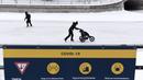 Para pemain skateboard melewati tanda tentang tindakan COVID-19 di Rideau Canal Skateway pada hari pembukaannya di Ottawa, Ontario, Kamis (28/1/2021). Kanal Rideau adalah Situs Warisan Dunia UNESCO. (Justin Tang/The Canadian Press via AP)