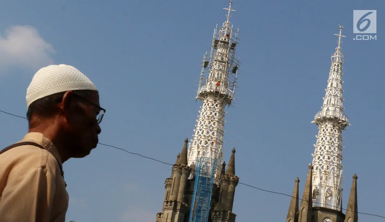 Warga melintas dekat pengerjaan konservasi bagian menara Gereja Katedral Jakarta, (19/5). Konservasi guna membersihkan, memelihara dan memperbaiki gereja berarsitektur neo-gothic yang merupakan cagar budaya di Jakarta. (Liputan6.com/Immanuel Antonius)