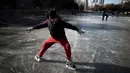 Aksi seorang warga saat bermain ice skating di sungai yang membeku di Beijing, China (21/1). Akibat membeku, Sungai ini menjadi objek wisata dadakan yang banyak diminati wisatawan. (AFP/Fred Dufour)