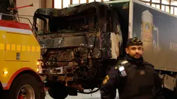 Petugas keamanan setempat berjaga di dekat truk yang menabrak kerumunan orang di Jalan Drottninggatan, pusat kota Stockholm, Swedia (8/4). (AP Photo / Markus Schreiber)