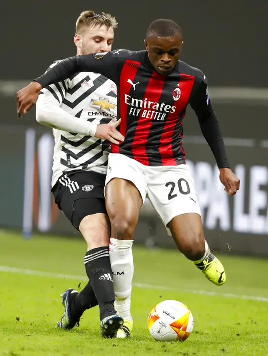 Pemain Manchester United Luke Shaw (kiri) dan pemain AC Milan Pierre Kalulu memperebutkan bola pada pertandingan leg kedua babak 16 besar Liga Europa di Stadion San Siro, Milan, Italia, Kamis (18/3/2021). Manchester United  menang 1-0. (AP Photo/Antonio Calanni)