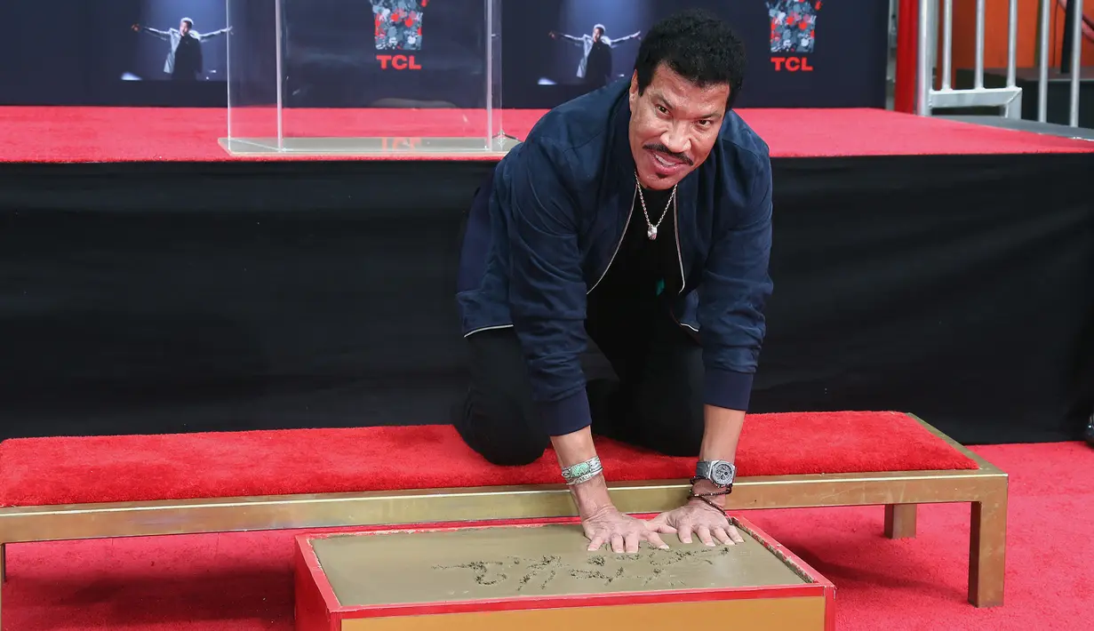 Penyanyi R&B AS, Lionel Richie mengabadikan cetak tangan dan kakinya di TCL Chinese Theatre, Hollywood, Rabu (7/3). Selama enam dekade aktif dalam dunia musik, Richie sukses menjual 100 juta album di seluruh dunia. (Tommaso Boddi/Getty Images/AFP)