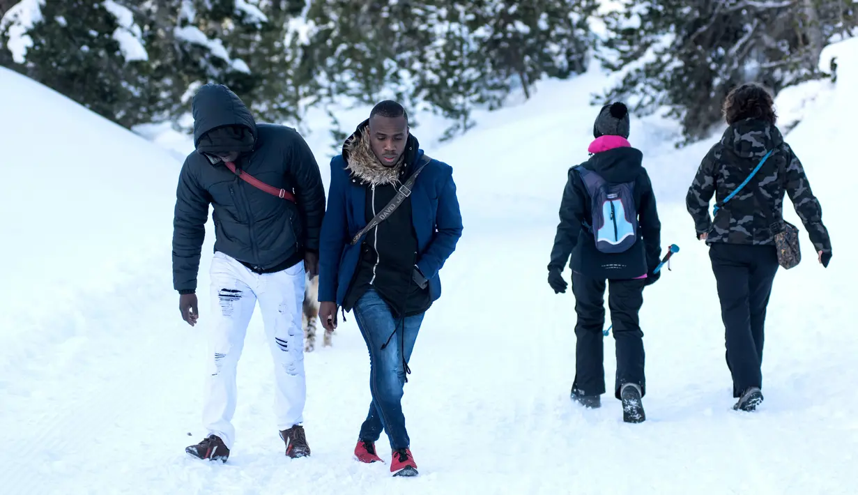 Dua imigran dari Pantai Gading berjalan menuju Colle della Scala (Col de l'Echelle) sebuah jalan yang tertutup salju, untuk melintasi perbatasan antara Italia dan Prancis di Pegunungan Alpen, Italia (13/1). (AFP/Piero Cruciatti)